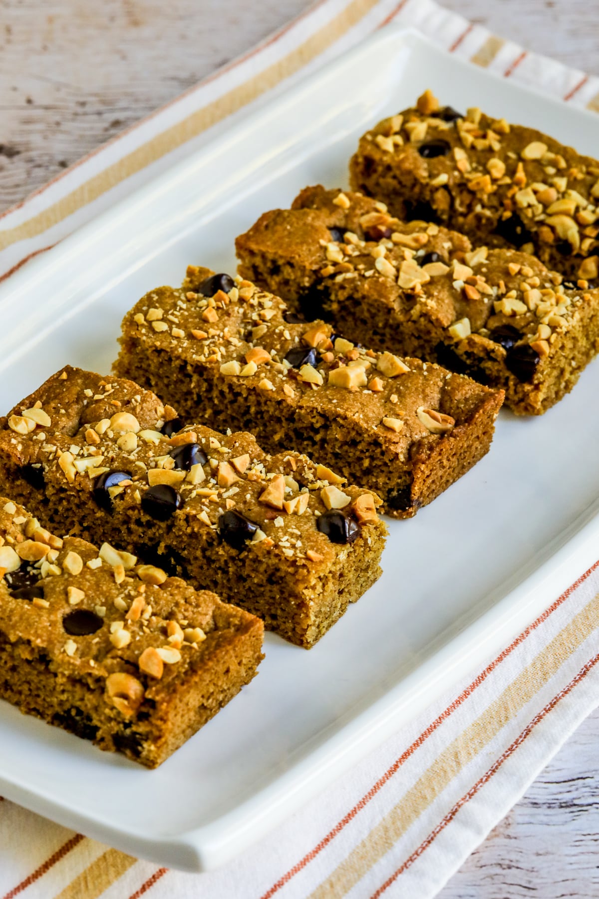 Peanut Butter Chocolate Chip Bars shown on serving platter on napkin.