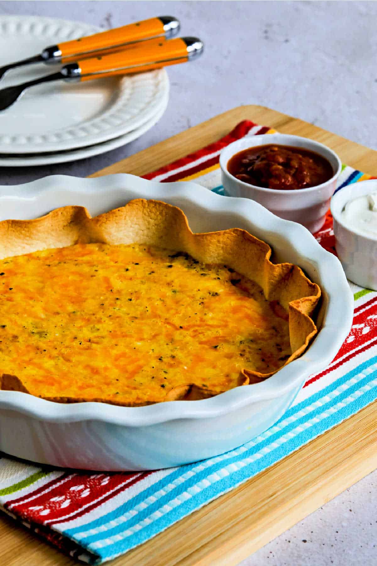 Tortilla Egg Bake with Cheese shown in pie dish with salsa and sour cream on the side.