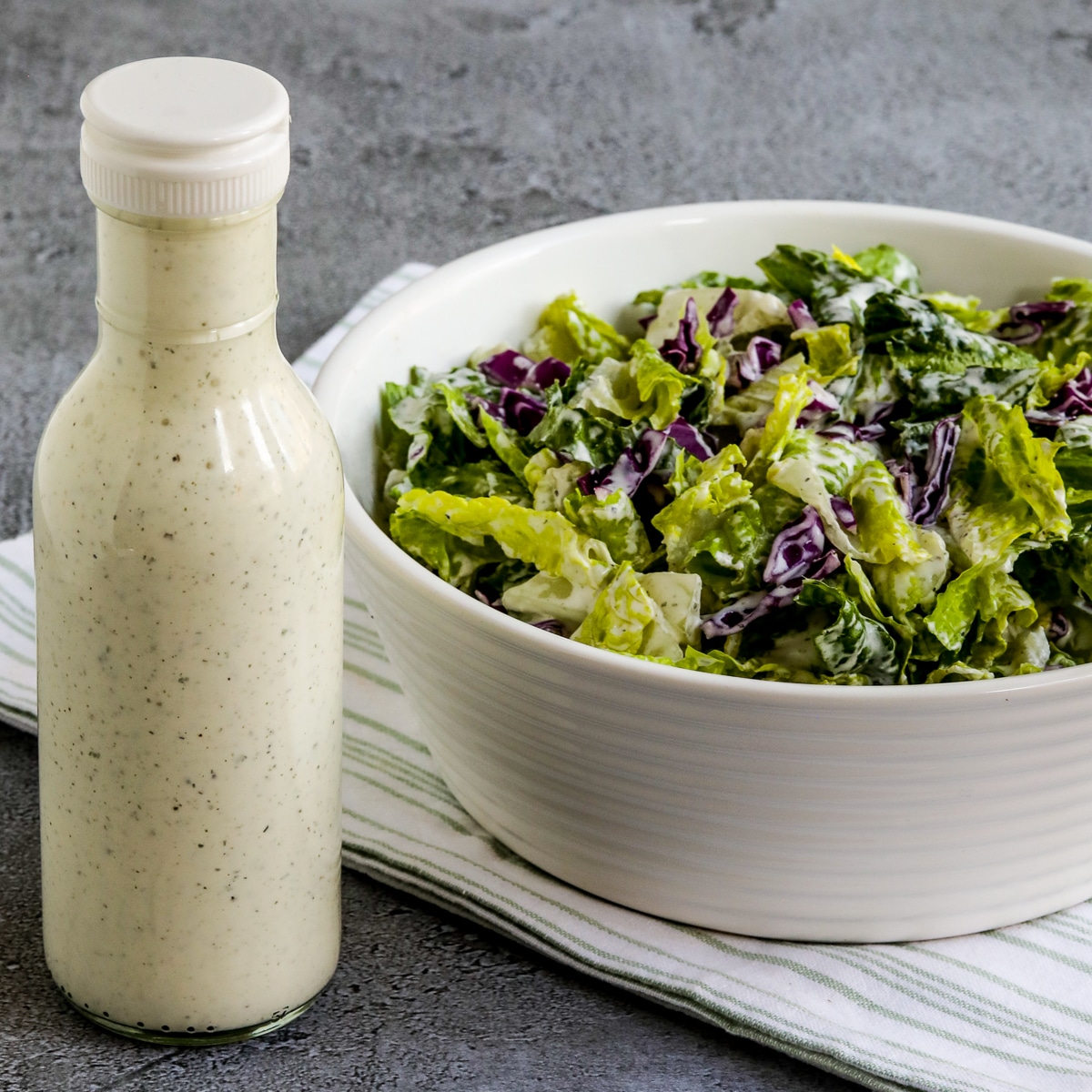 Square image for BYU Creamery Ranch Dressing (Copycat Recipe) showing dressing in bottle with salad next to it.