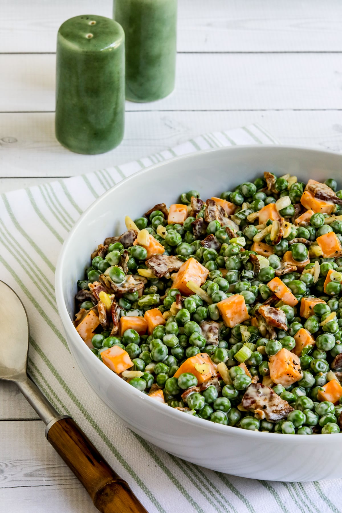 Bacon and Pea Salad in white bowl on green and white napkin.