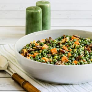 Square image of Bacon and Pea Salad in bowl with spoon and salt-pepper shakers.