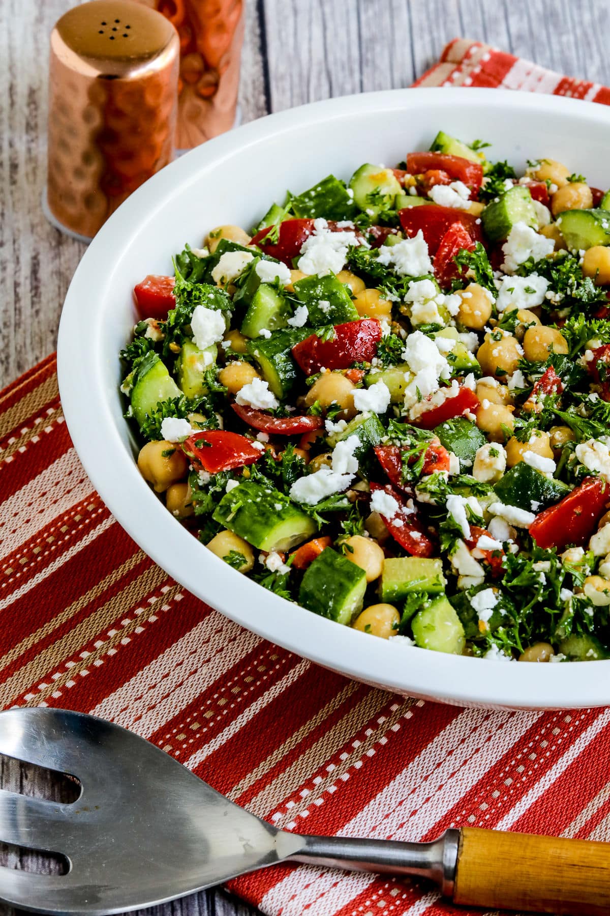 Tomato Cucumber Chickpea Salad in serving bowl with large serving spoon.