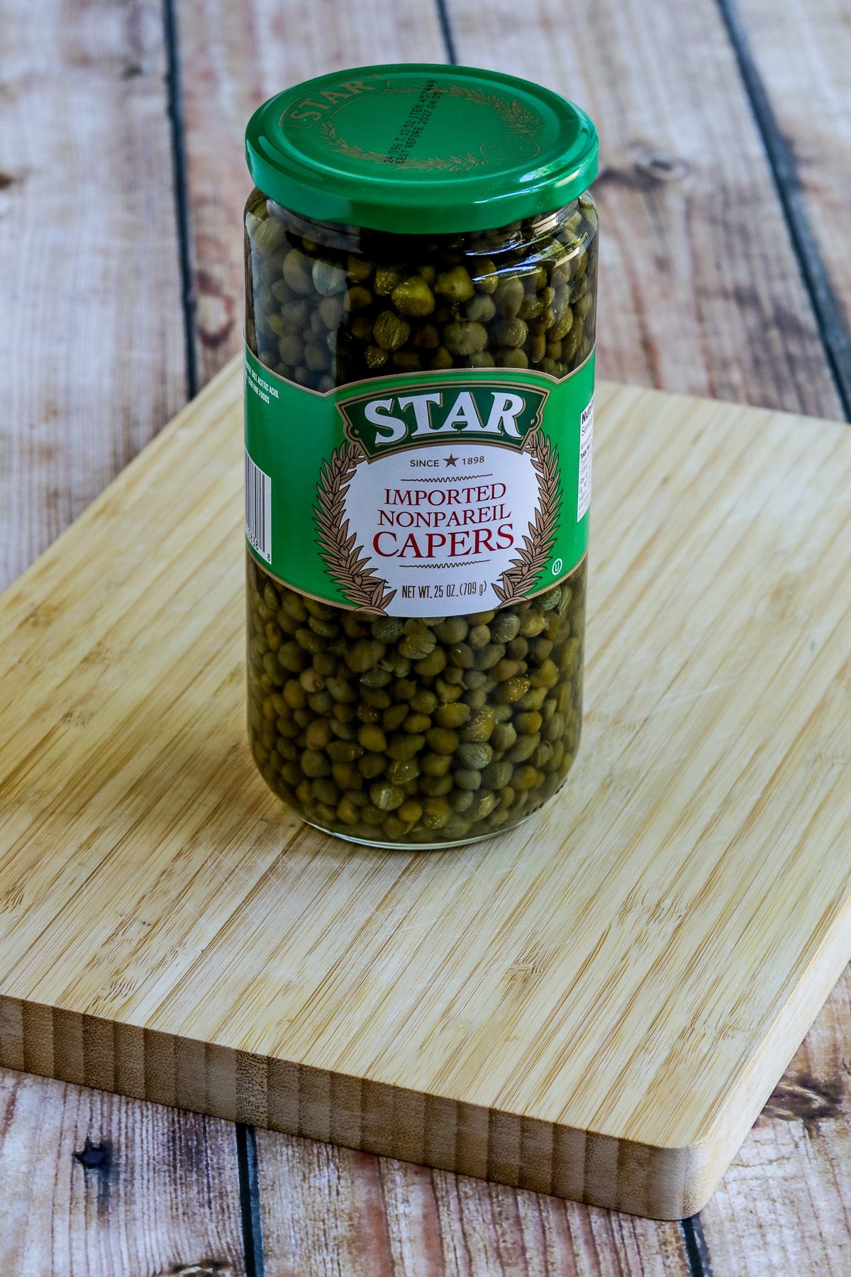 Jar of Capers on Cutting Board.
