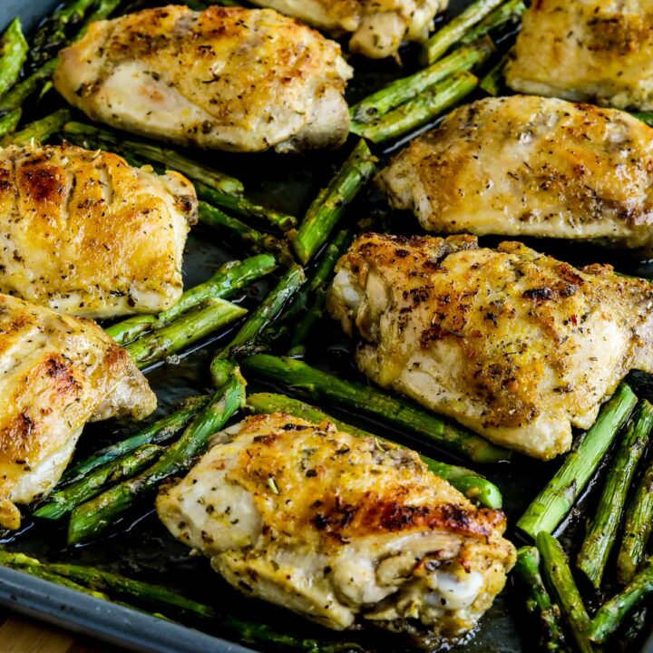 Sheet Pan Chicken Thighs and Asparagus shown on sheet pan on cutting board.