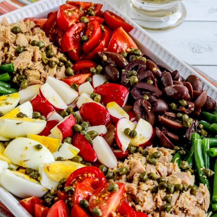 Nicoise Tuna Salad Recipe shown with salad arranged on platter and dressing in back.