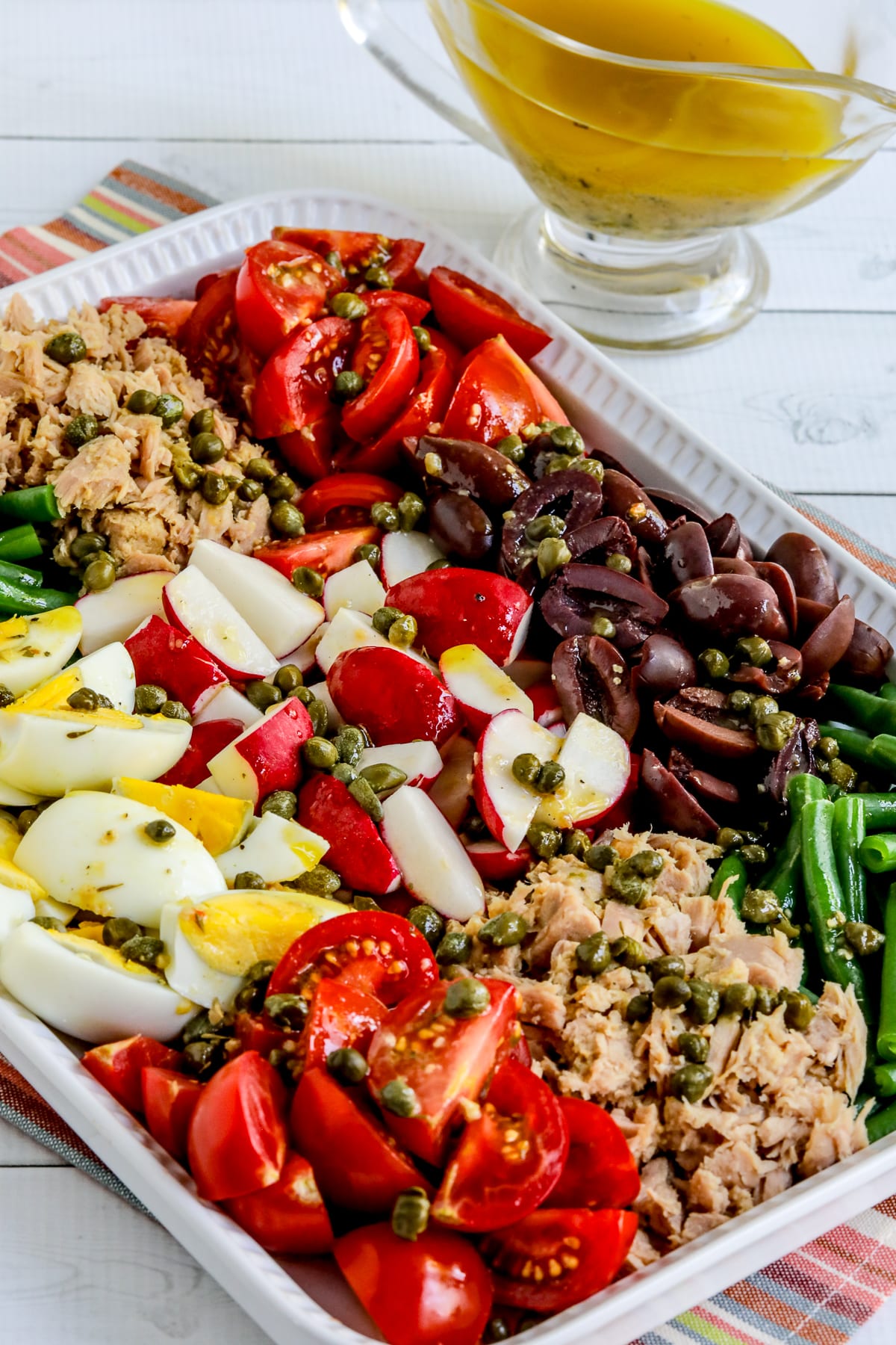 Nicoise Tuna Salad Recipe shown with salad arranged on platter and dressing in back.