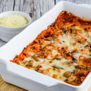 Square featured image for Cottage Cheese Pasta Bake with Mushrooms shown in baking dish with Parmesan in back.