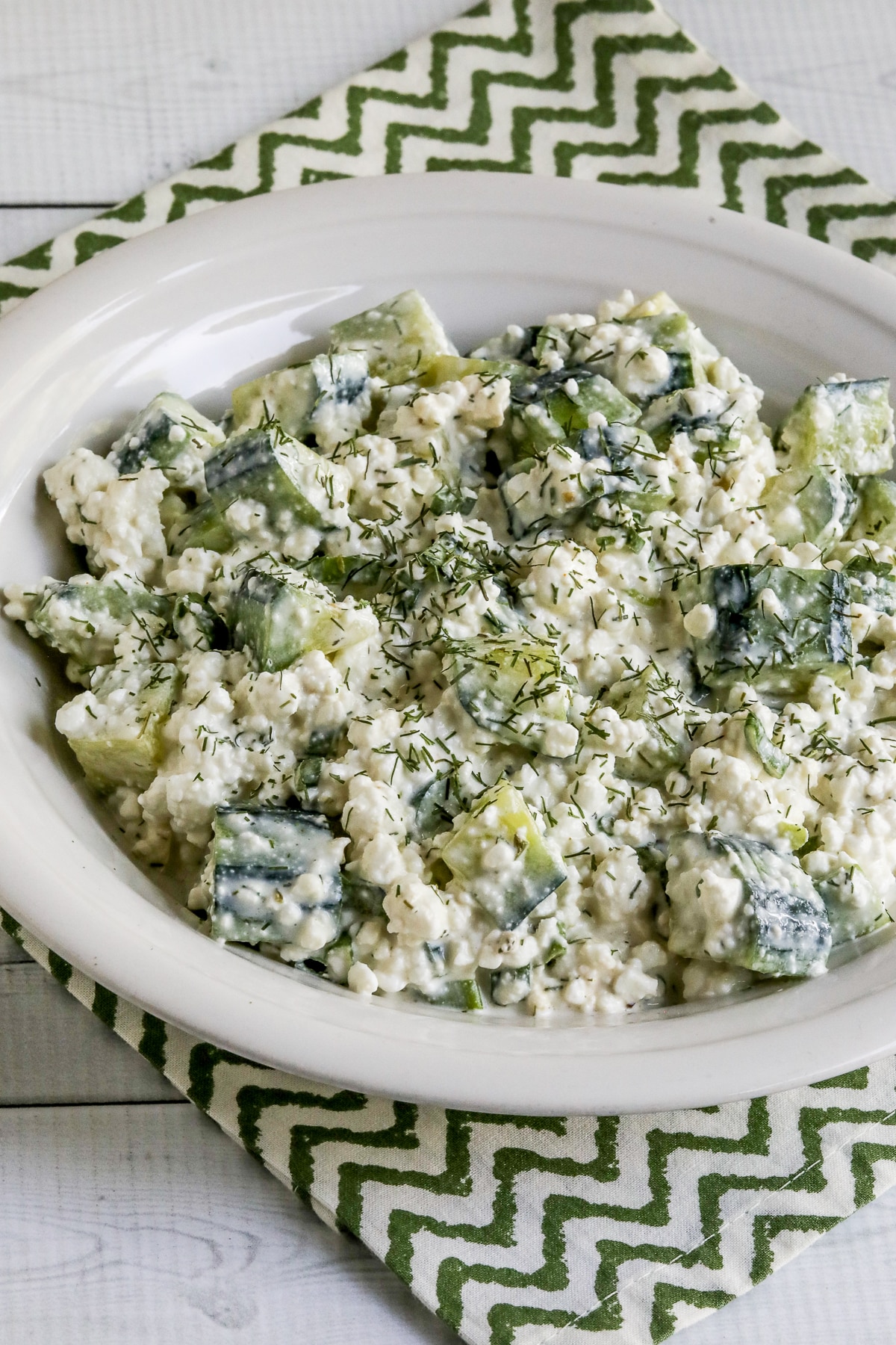 Cottage Cheese Cucumber Salad shown in serving bowl with dill weed sprinkled on top.